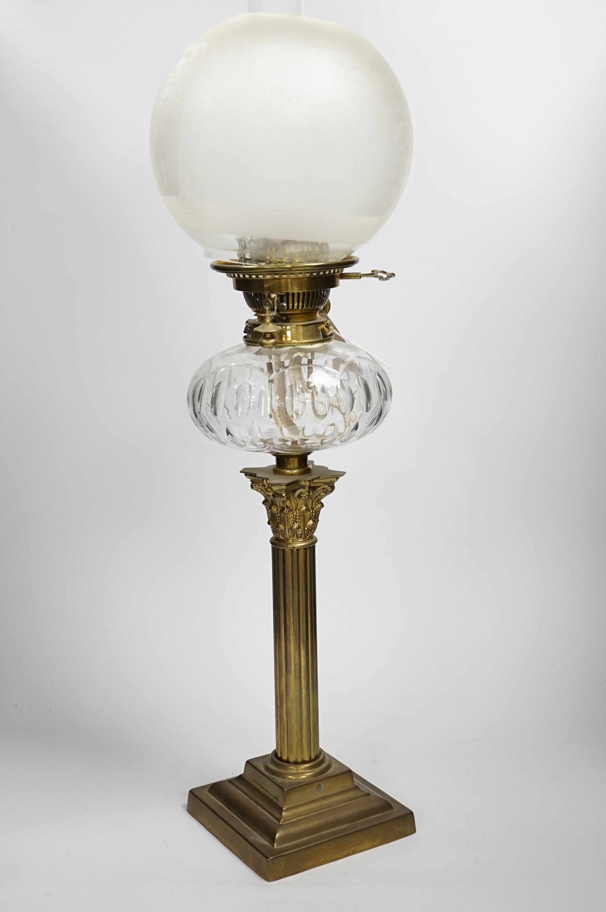 A Victorian brass oil lamp with glass reservoir and etched shade, 70cm high